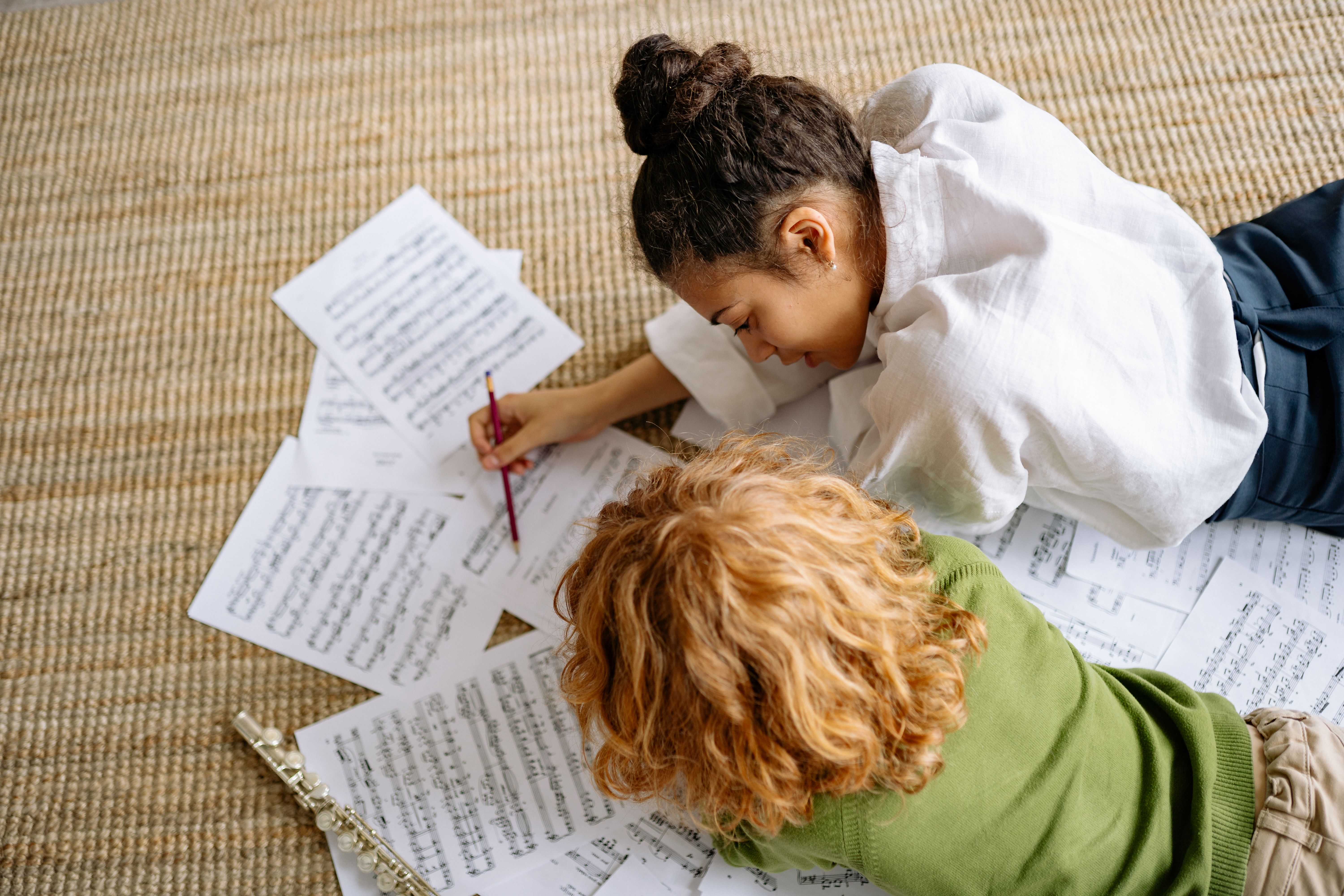 Primary school pupil reviewing music sheets with a teacher as part of a school arts enrichment activity